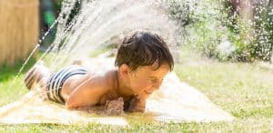 bimbo in giardino si diverte sotto l'acqua