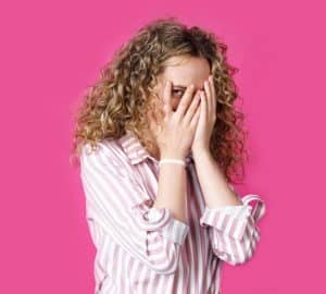 donna che si copre la faccia con le mani e spia da un occhio