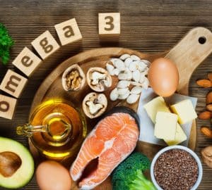 salmone, avocado, semi, noci, olio su tavolo di legno con scritta omega-3