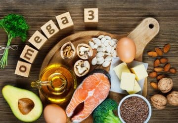 salmone, avocado, semi, noci, olio su tavolo di legno con scritta omega-3