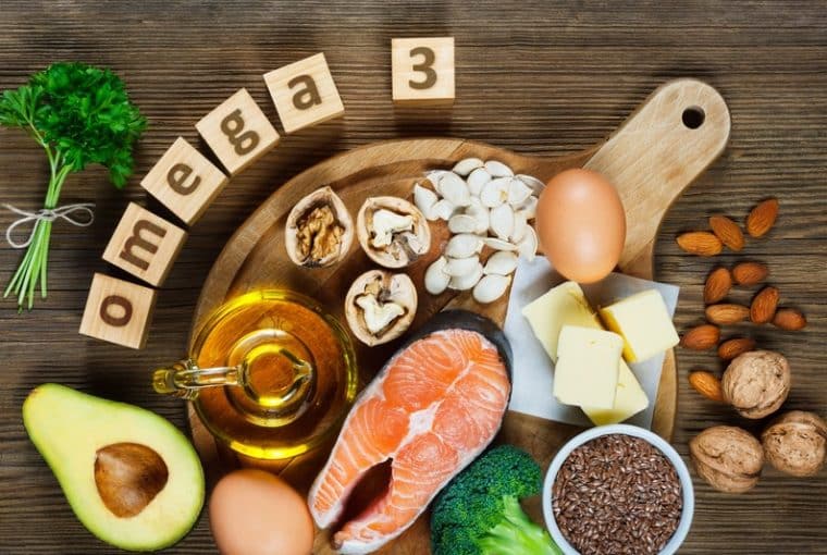 salmone, avocado, semi, noci, olio su tavolo di legno con scritta omega-3