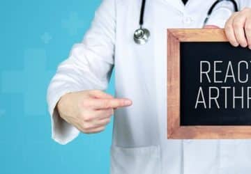 medico con in mano una lavagnetta con su scritto artriti reattive in inglese