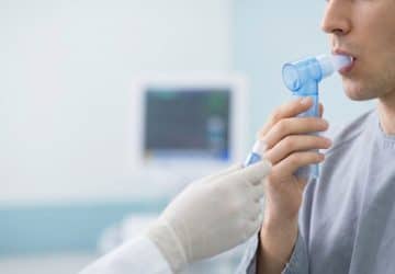 La spirometria aiuta a valutare come lavorano i polmoni: Primo piano di mani che tengono un misuratore di picco di flusso…