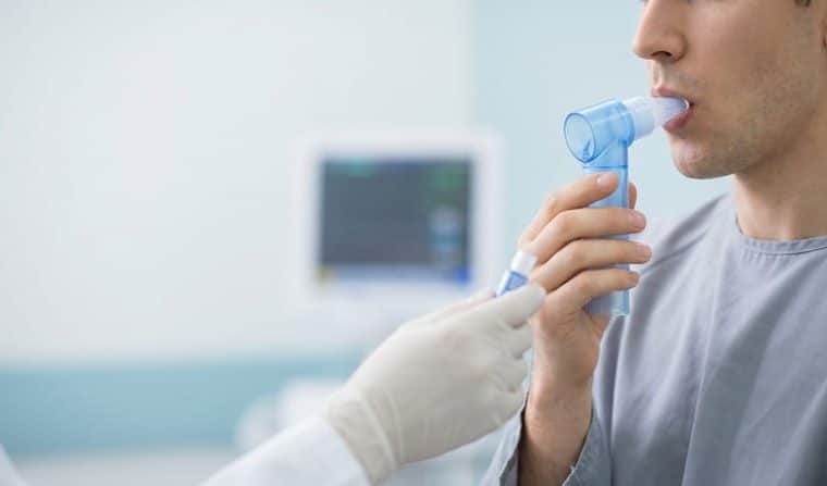 La spirometria aiuta a valutare come lavorano i polmoni: Primo piano di mani che tengono un misuratore di picco di flusso…